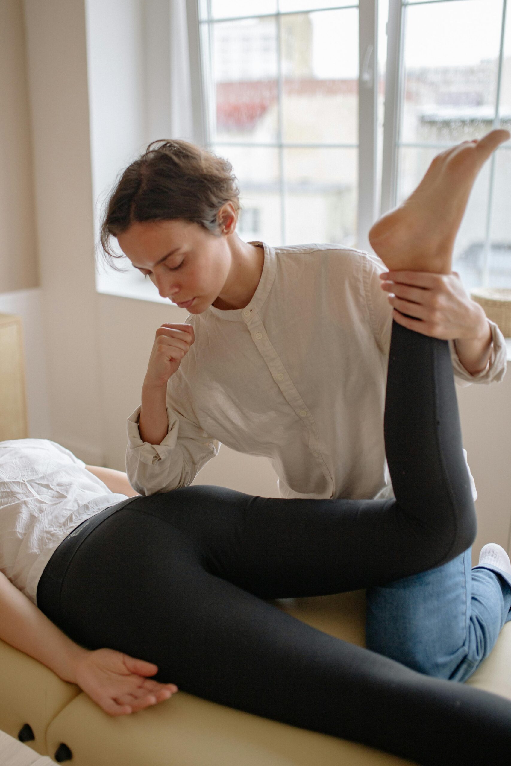 Massage therapist performing a leg stretch on a client indoors. Focus on therapeutic care.